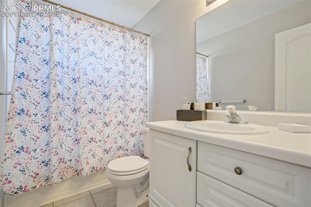 Full bathroom with vanity, light tile patterned floors, and shower / bathtub combination with curtain