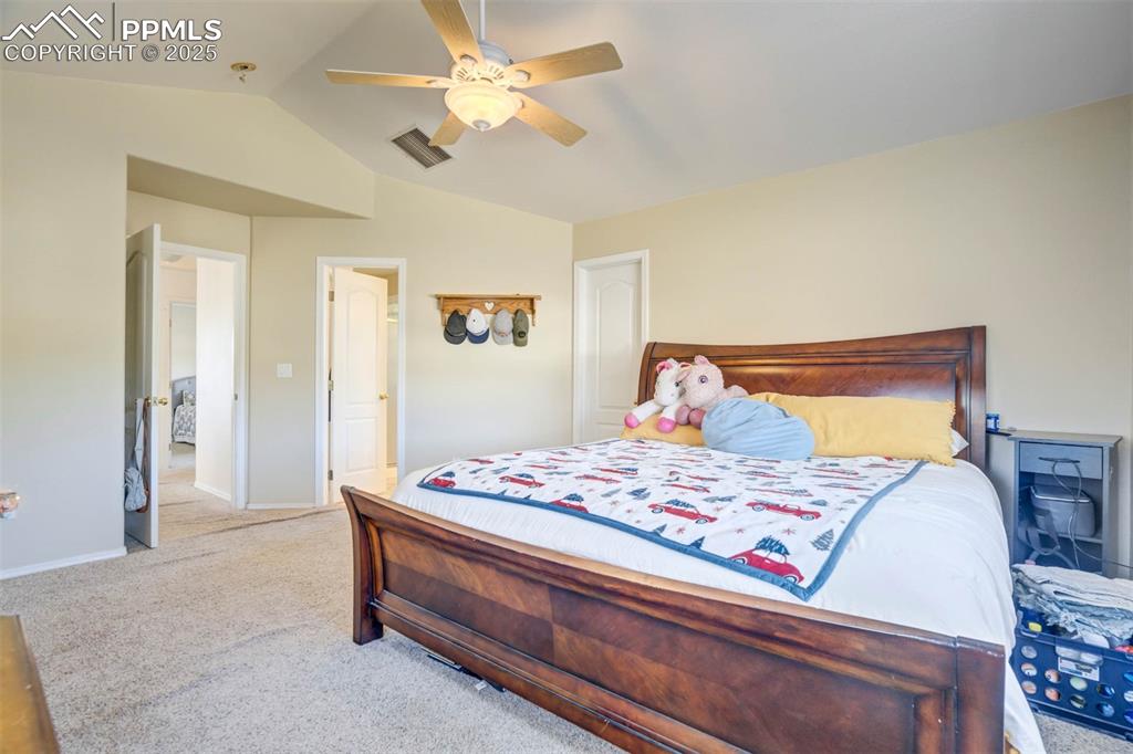 Carpeted bedroom featuring vaulted ceiling and ceiling fan