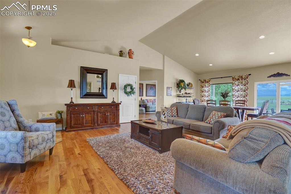 Living area featuring light wood-style floors, high vaulted ceiling, and recessed lighting
