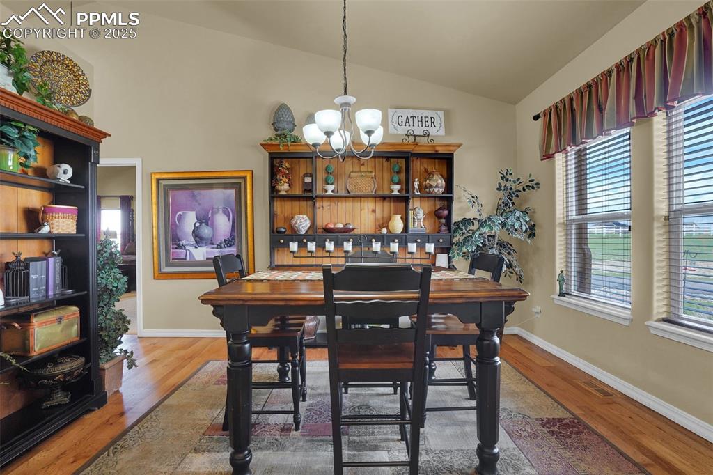 Dining space featuring lofted ceiling, baseboards, wood finished floors, and an inviting chandelier