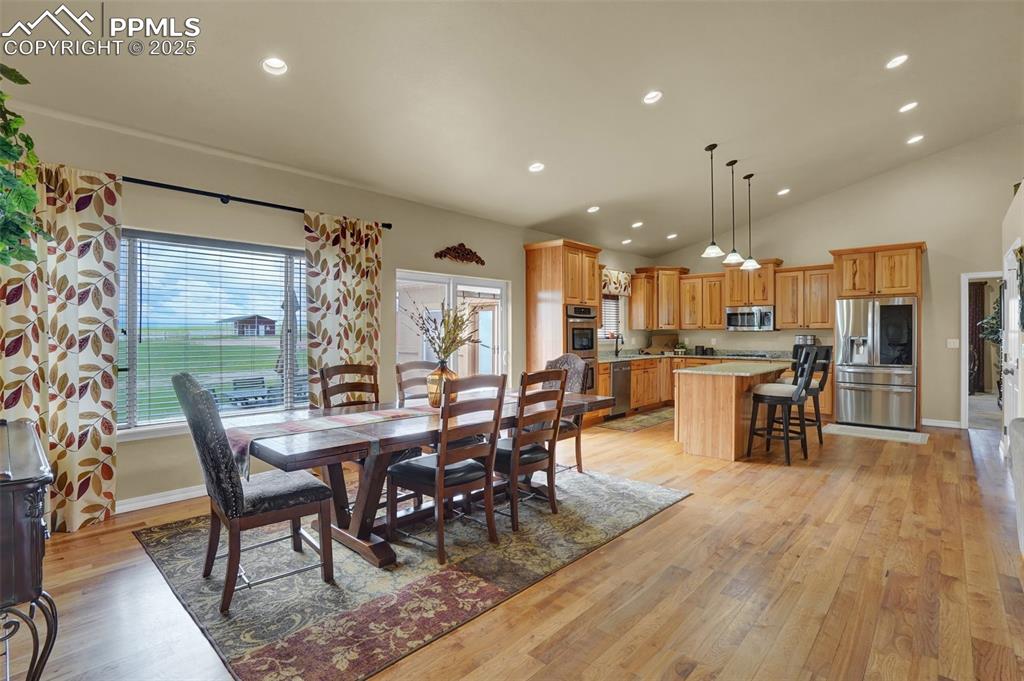 Dining room featuring high vaulted ceiling, light wood-type flooring, baseboards, and recessed lighting
