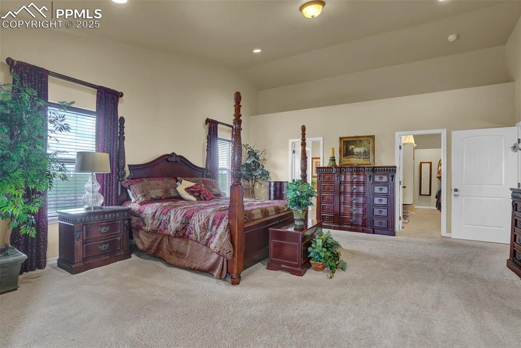 Carpeted primary bedroom featuring lofted ceiling and recessed lighting