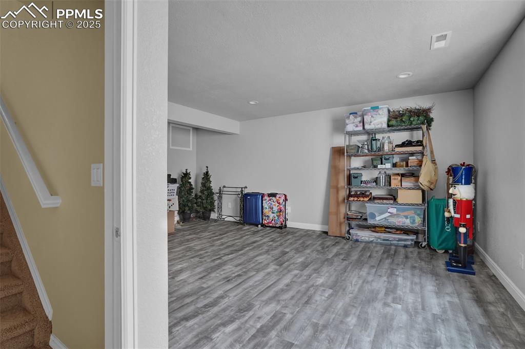 Below grade area featuring wood finished floors, visible vents, baseboards, and stairs