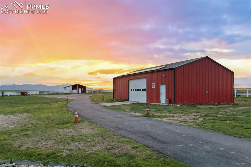 Outdoor structure at dusk featuring an outbuilding, a mountain view, an outdoor structure, fence, and a yard