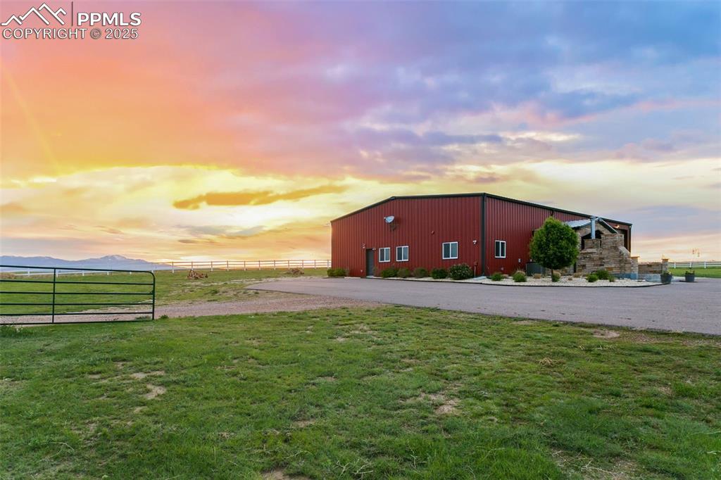 Outdoor structure at dusk with an outbuilding, a yard, an outdoor structure, and fence