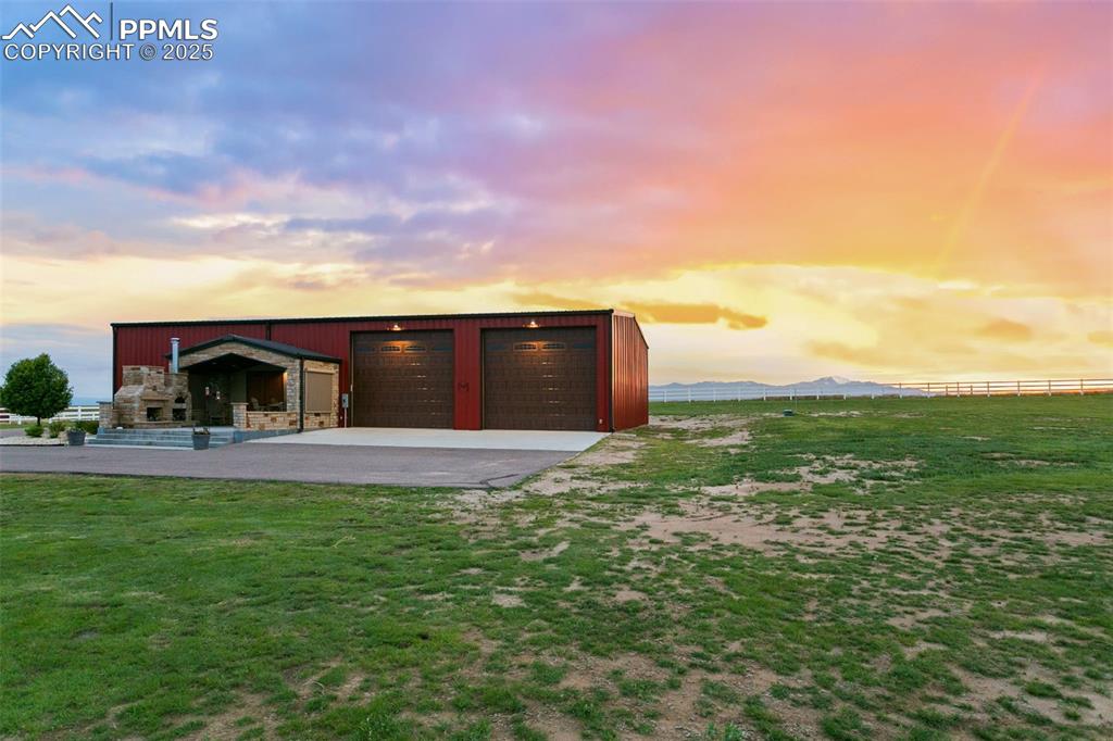 Back of house at dusk with an outbuilding, a mountain view, and a lawn