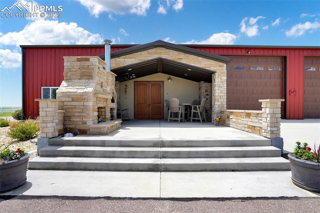Barndominium front view with stone fireplace and outdoor pizza oven. 