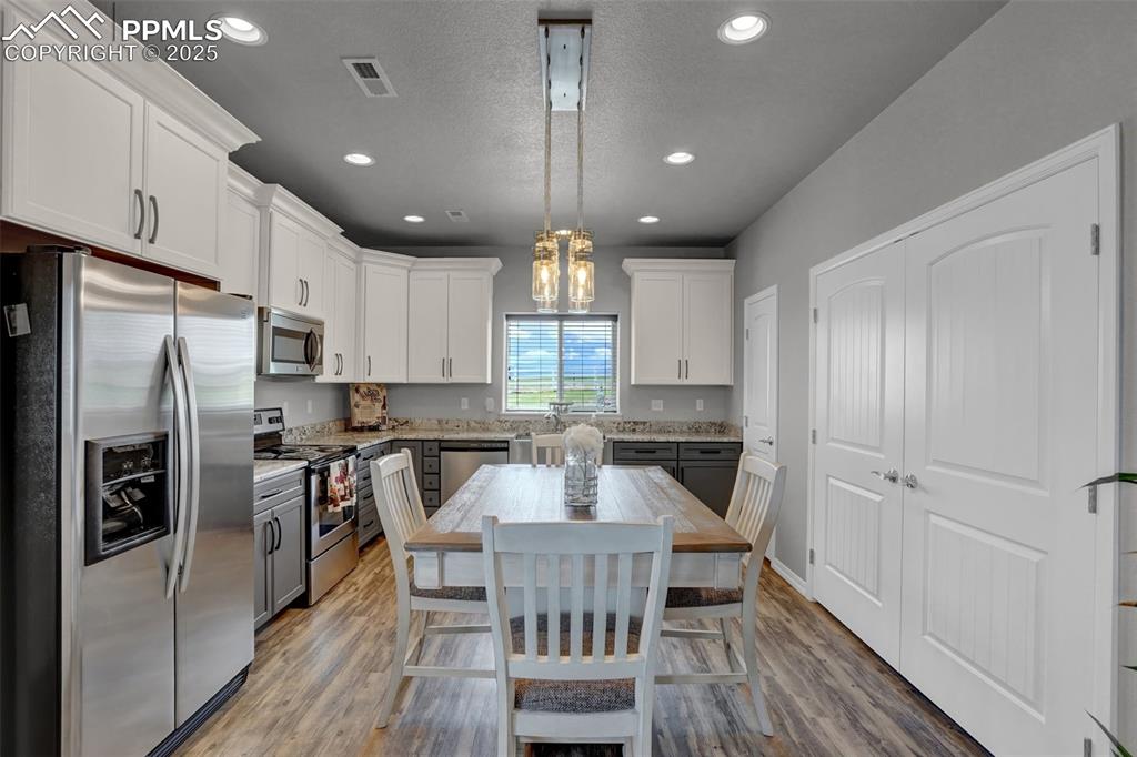 Kitchen featuring appliances with stainless steel finishes, light wood-style floors, visible vents, and white cabinets