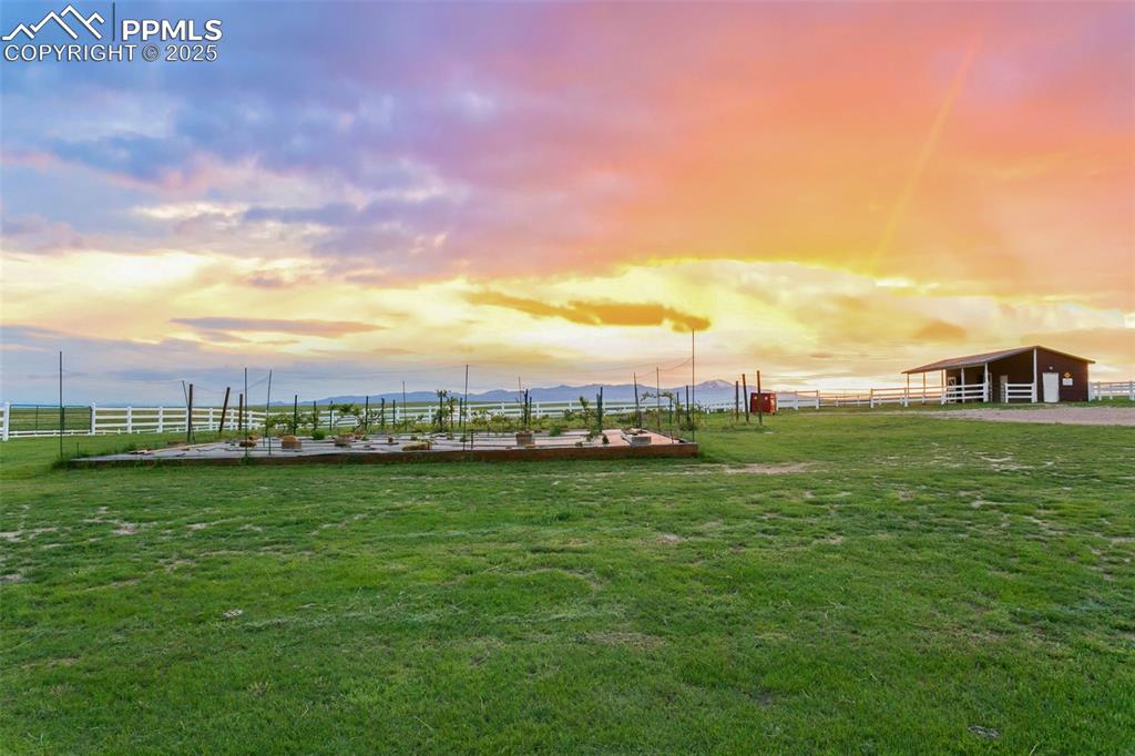 Yard at dusk featuring the horse stables, vineyard and garden