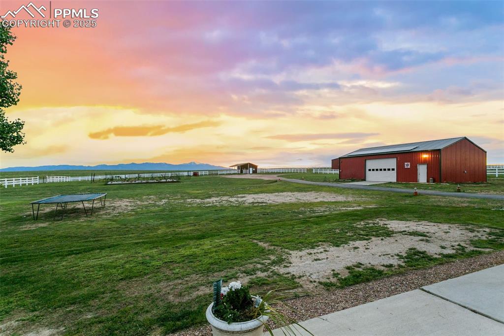 Yard at dusk with unobstructed views of Pikes Peak, barn, a trampoline