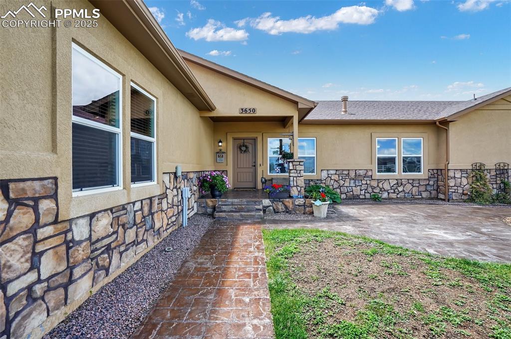 Entrance to property featuring stone siding and stucco siding