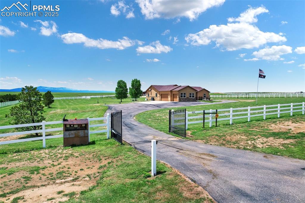 View of road Leading up tp home and front entry gates featuring a gate, a gated entry, aphalt driveway, and a rural view