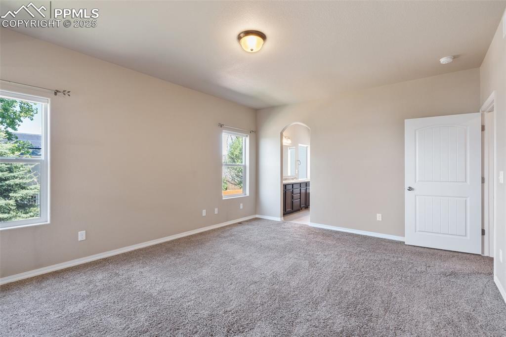 Empty room with light colored carpet and arched walkways - Main Level
