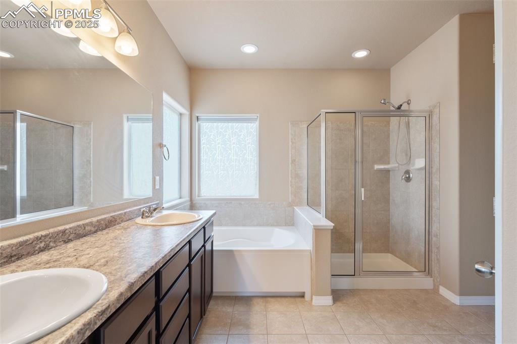 Full bath with a bath, a stall shower, double vanity, light tile patterned flooring, and recessed lighting