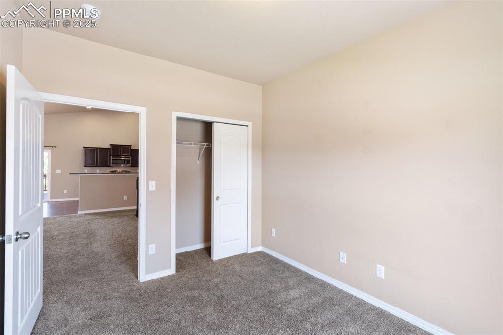 Office/Bedroom on main level - Unfurnished bedroom with dark carpet and a closet
