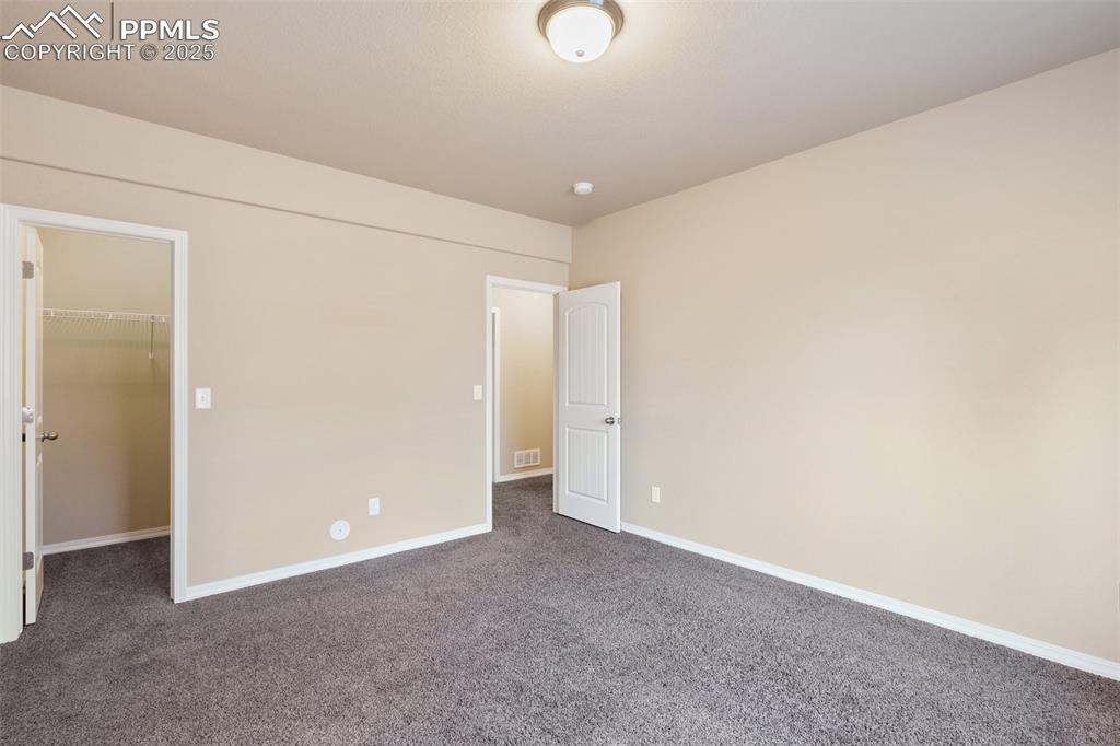 Bedroom Basement Level - Unfurnished bedroom with a walk in closet and dark carpet