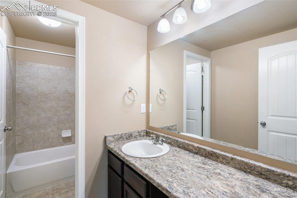 Basement Full bathroom with vanity, shower / washtub combination, and light tile patterned flooring