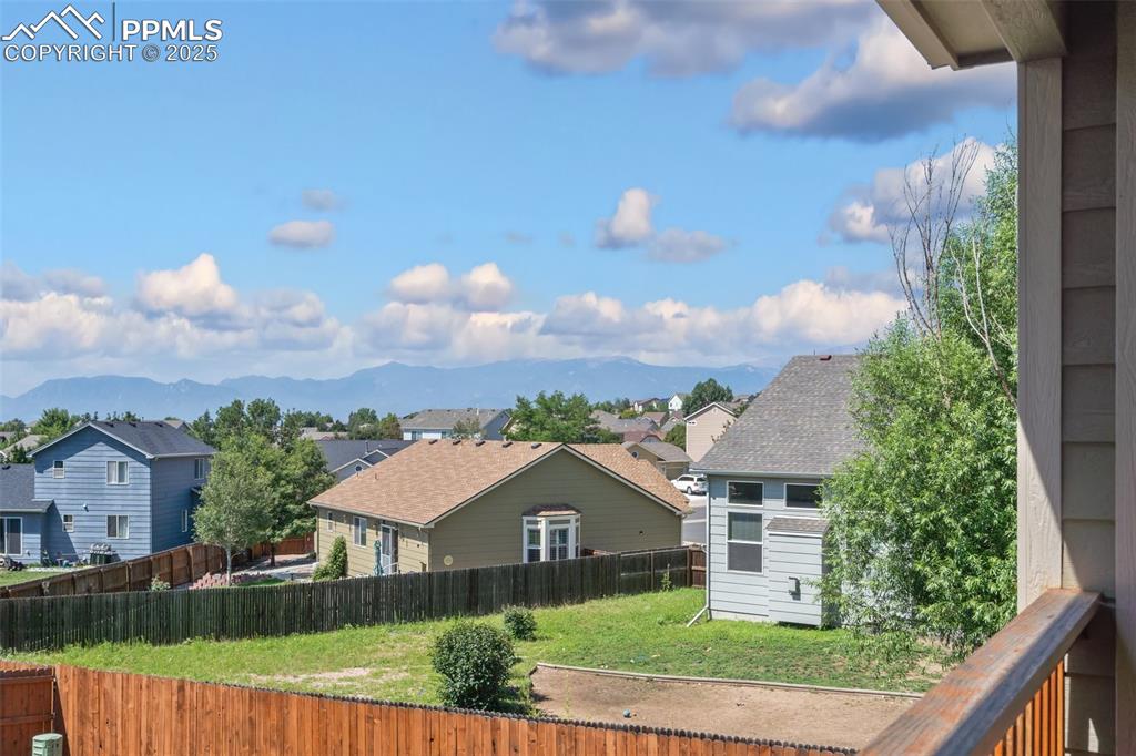 Rear view of house featuring a residential view, a shingled roof, a mountain view, and a balcony