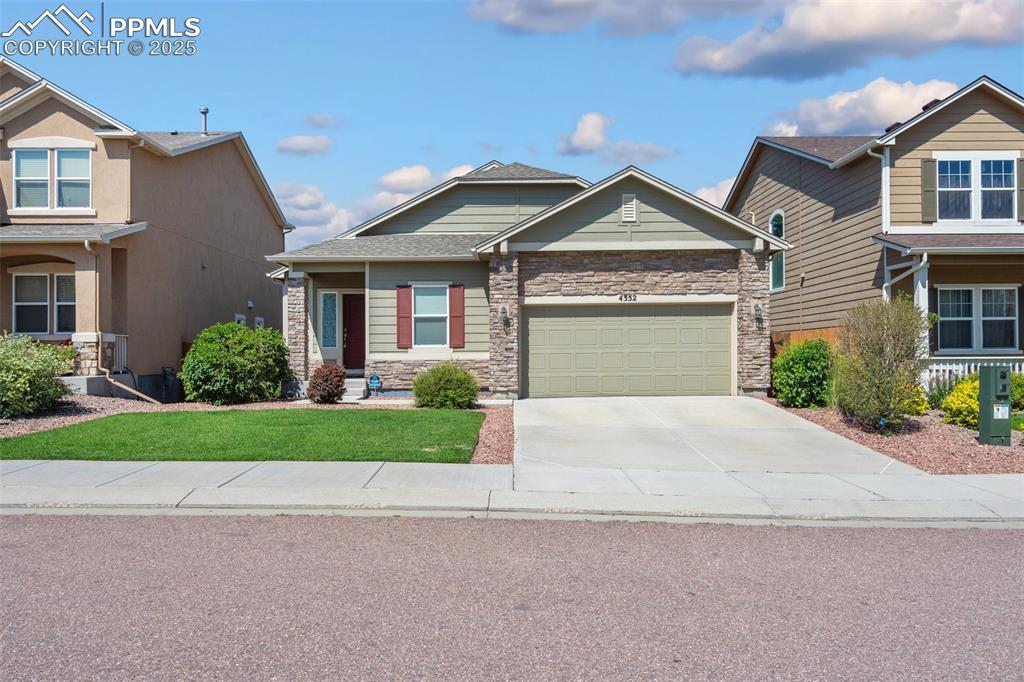 Craftsman-style home with stone siding, concrete driveway, an attached garage, and a front lawn