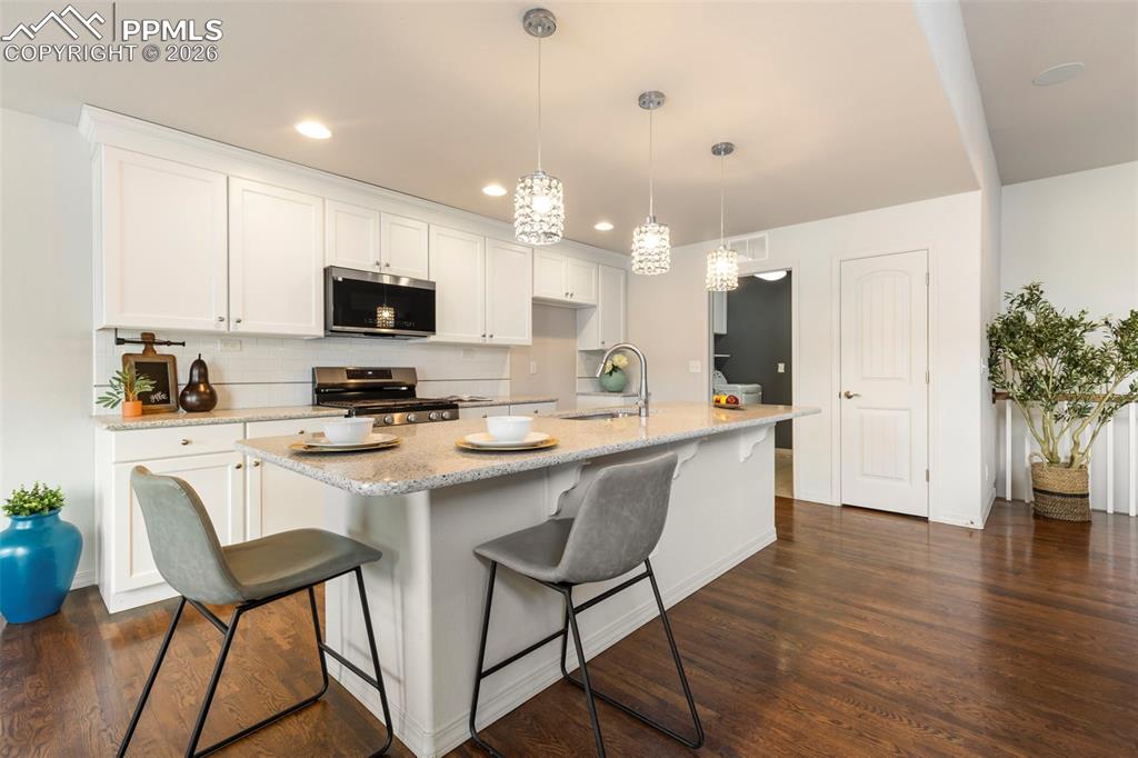 Kitchen view highlighting gas range, stone countertops, and extended counter space for food prep and entertaining.