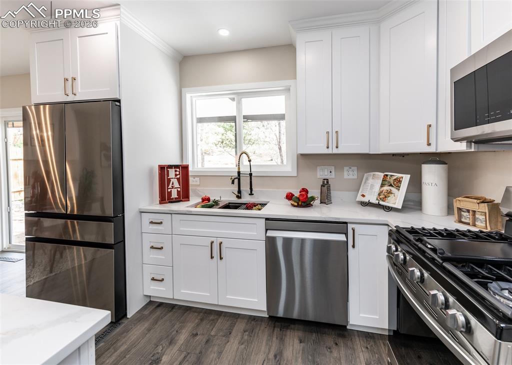 Kitchen featuring appliances with stainless steel finishes, white cabinets, and dark wood-style flooring