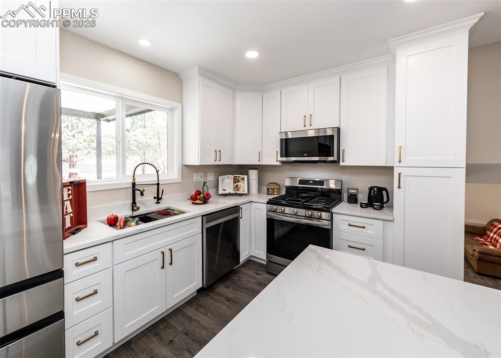 Kitchen featuring appliances with stainless steel finishes, white cabinets, dark wood-type flooring, and recessed lighting