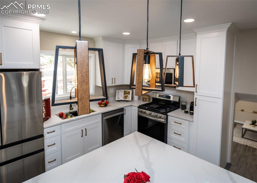 Kitchen featuring white cabinetry, stainless steel appliances, light stone countertops, and recessed lighting