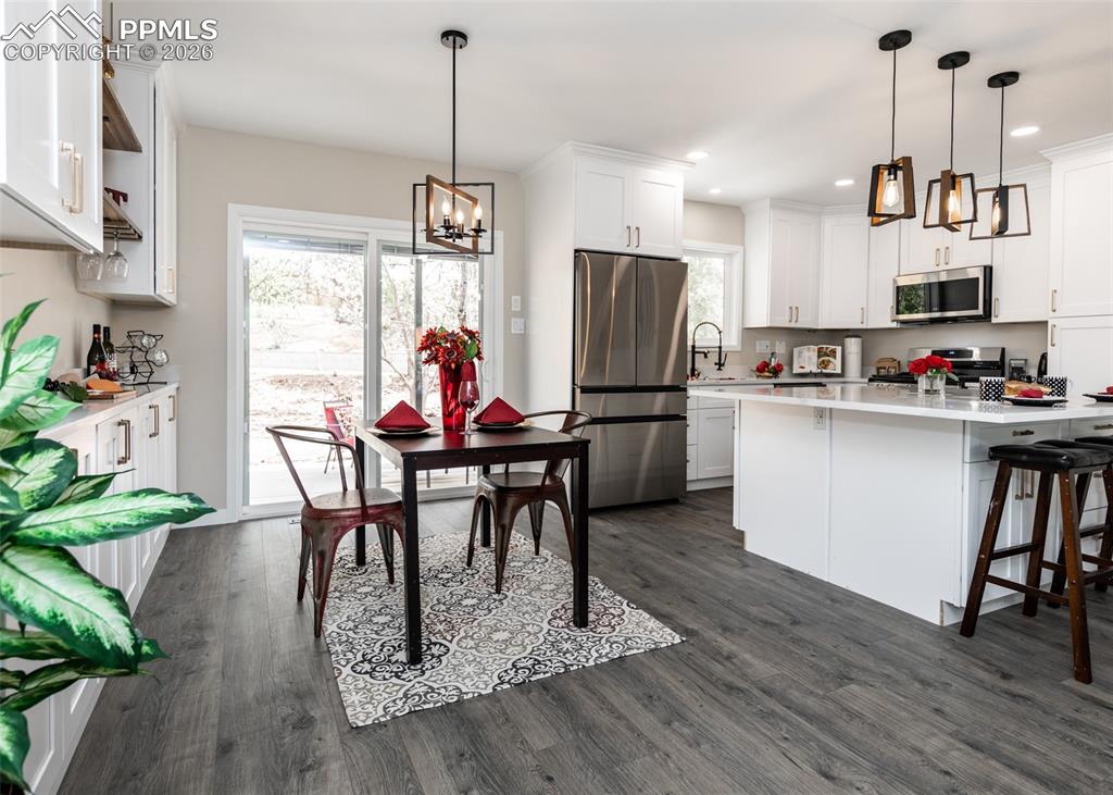 Kitchen with stainless steel appliances, white cabinetry, pendant lighting, a kitchen breakfast bar, and recessed lighting