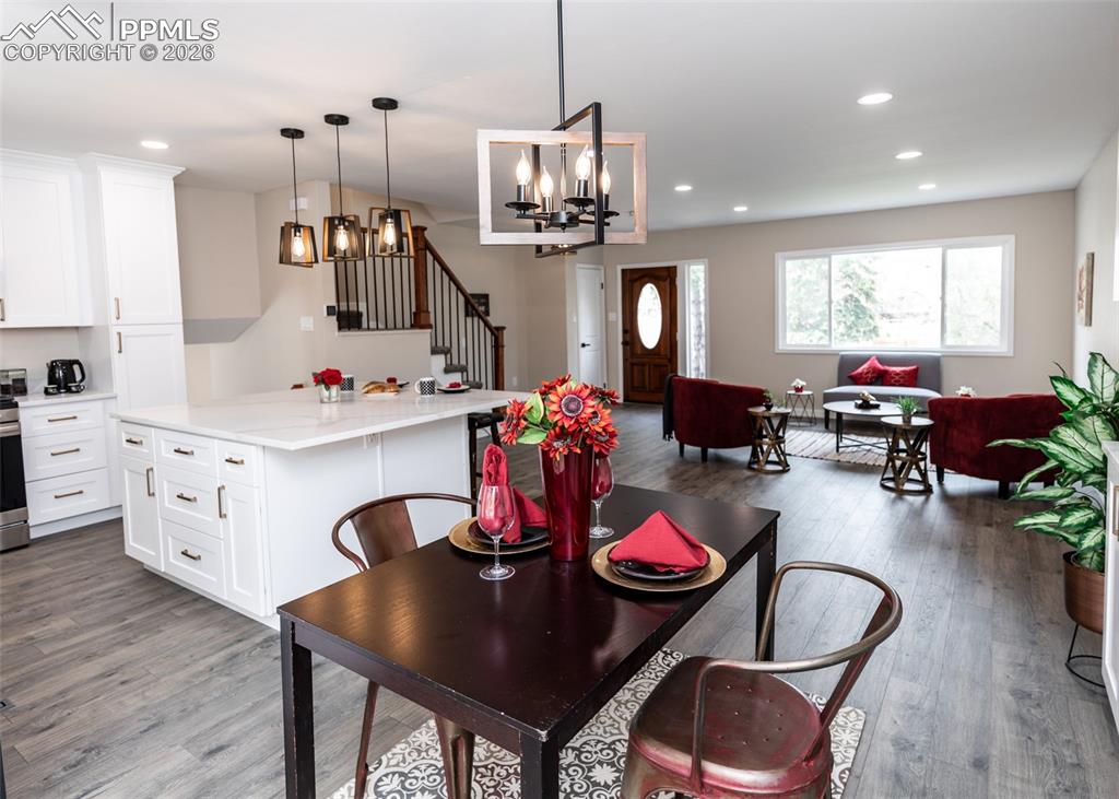 Dining space featuring stairs, recessed lighting, dark wood-style floors, and a chandelier