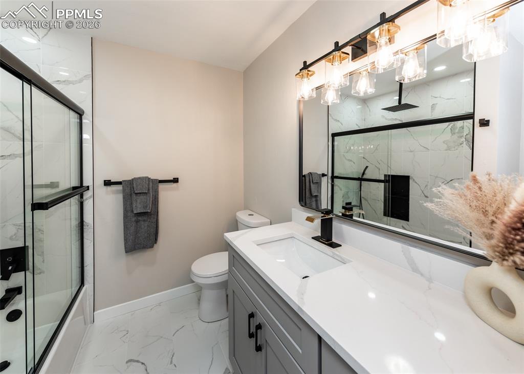 Full bathroom with light marble finish floors, vanity, and a combined bath / shower with rainfall shower