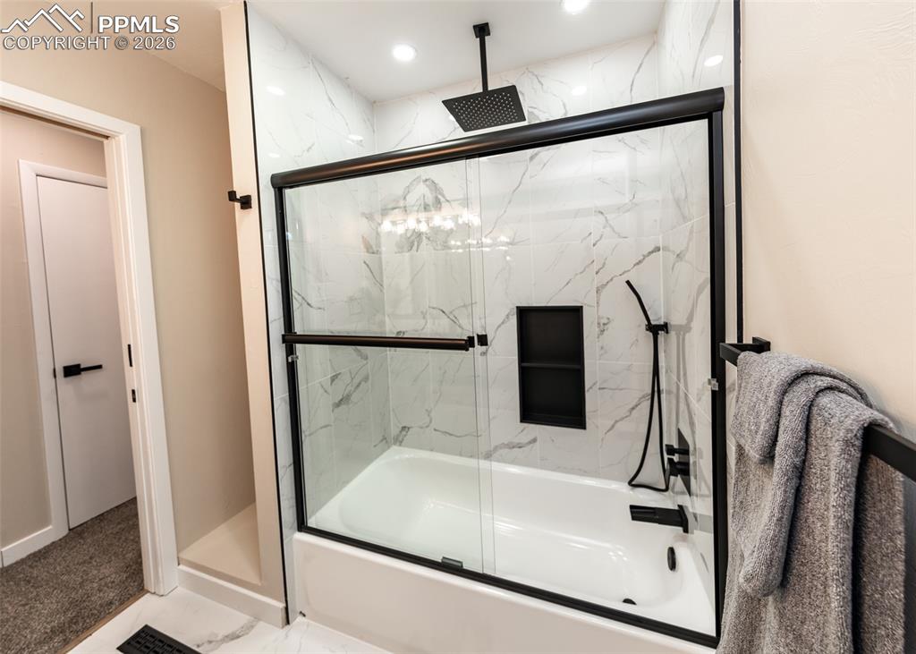 Full bath with a combined bath / shower with rainfall shower, marble look tile flooring, and recessed lighting