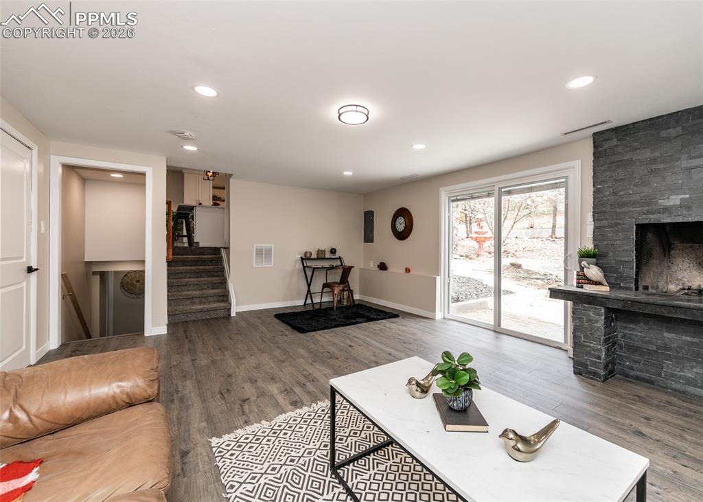 Living room with a fireplace, wood finished floors, stairs, and recessed lighting