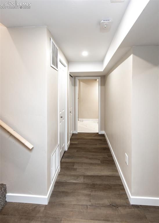Hallway with dark wood-style flooring and recessed lighting