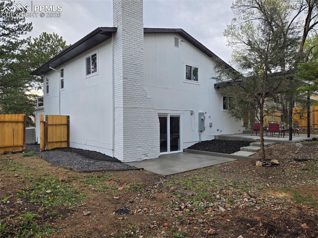 Back of property featuring a patio area, a chimney, and brick siding