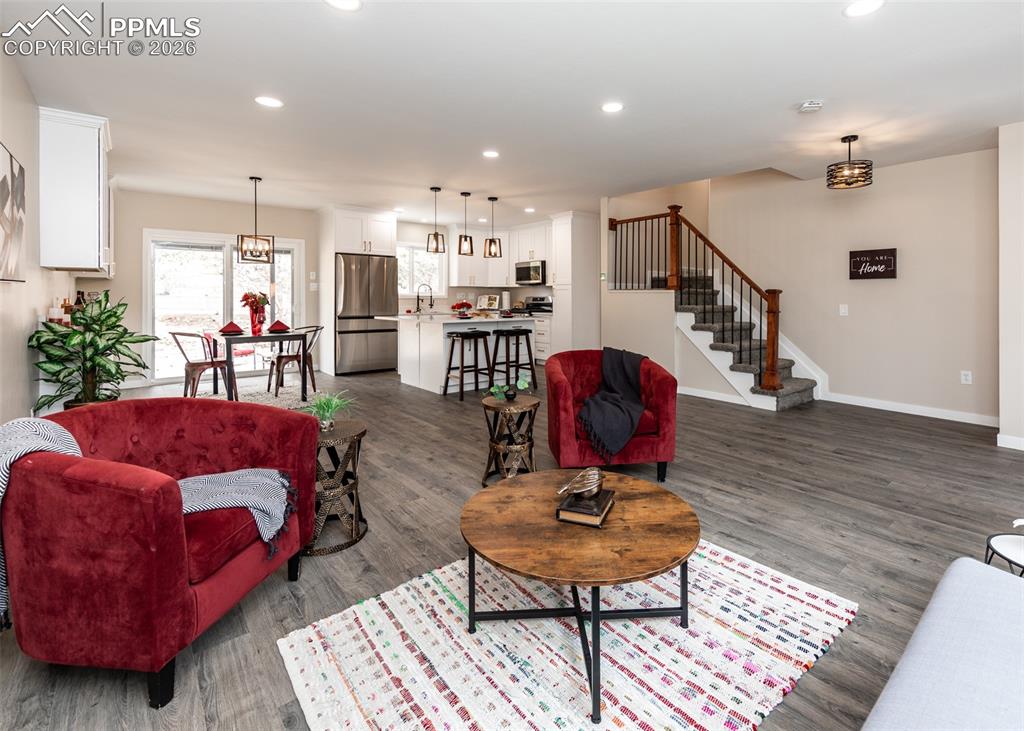 Living area featuring recessed lighting, stairs, and dark wood-style floors