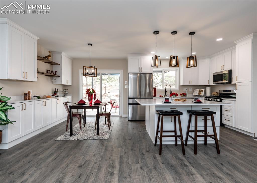 Kitchen featuring stainless steel appliances, white cabinets, pendant lighting, a kitchen island, and recessed lighting