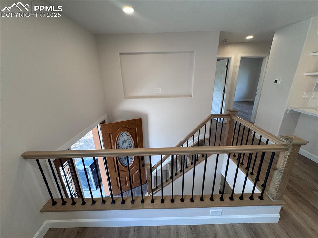 Stairs with wood finished floors and recessed lighting