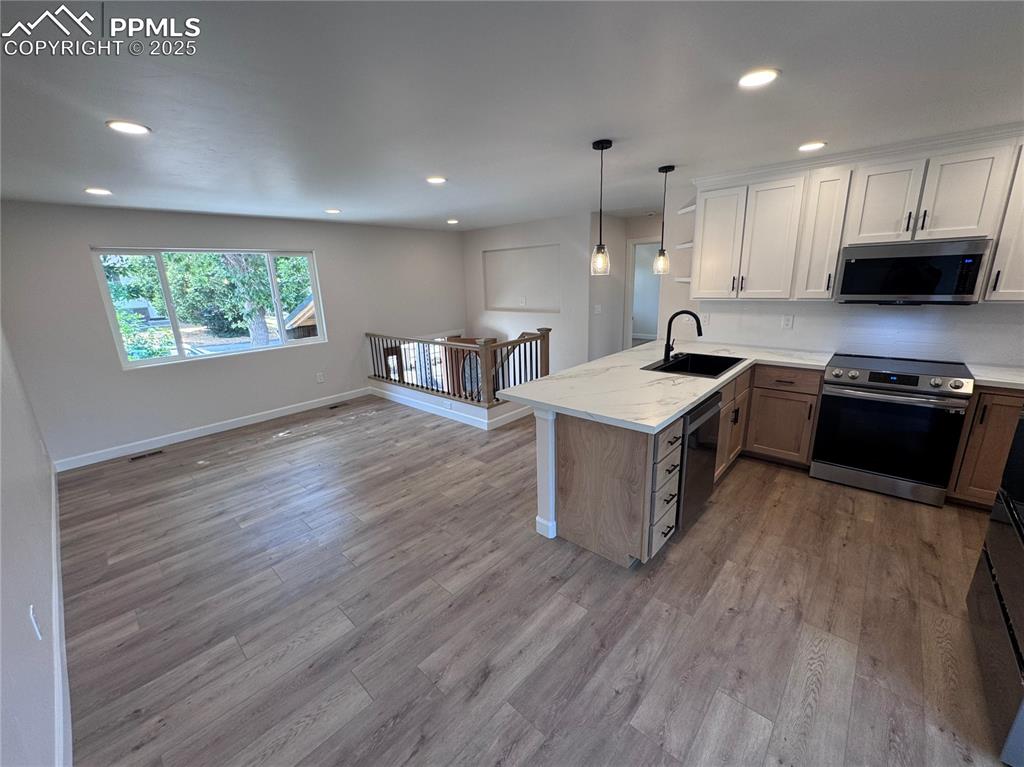 Kitchen featuring stainless steel appliances, hanging light fixtures, white cabinetry, a peninsula, and recessed lighting
