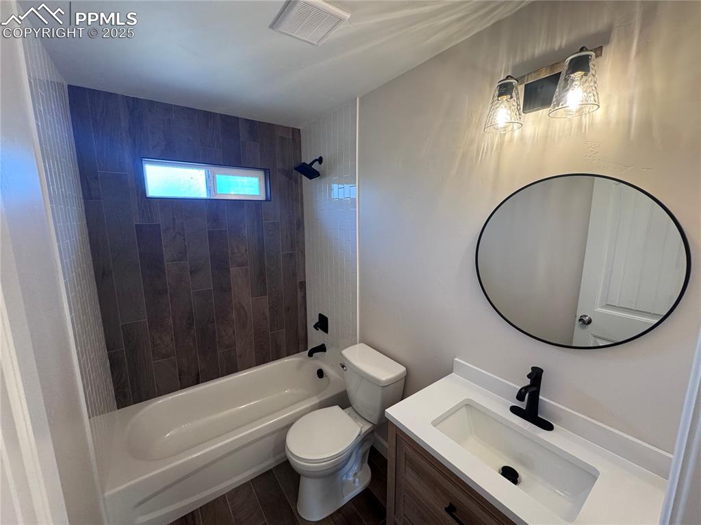 Bathroom with shower / bathtub combination, vanity, and dark wood-style flooring
