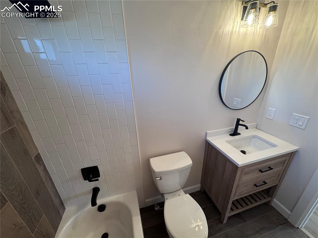Full bathroom with vanity, shower / bathtub combination, and dark tile patterned flooring