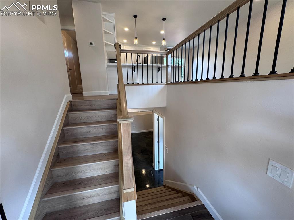 Stairway with wood finished floors and recessed lighting