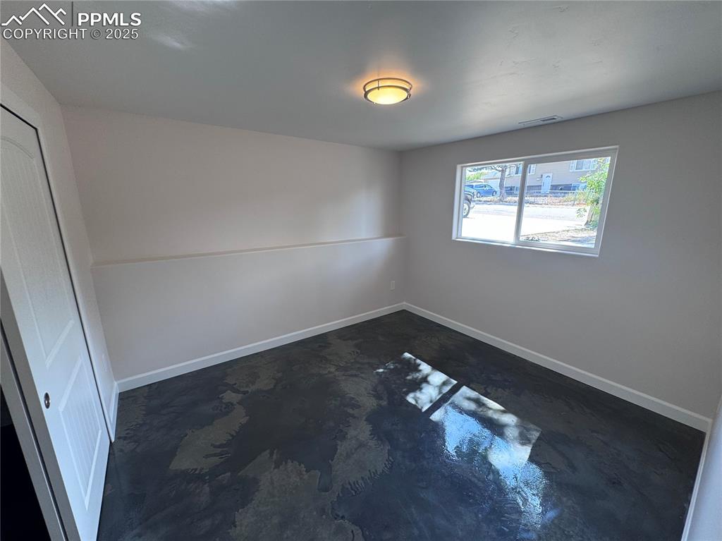 Empty room with finished concrete flooring and baseboards