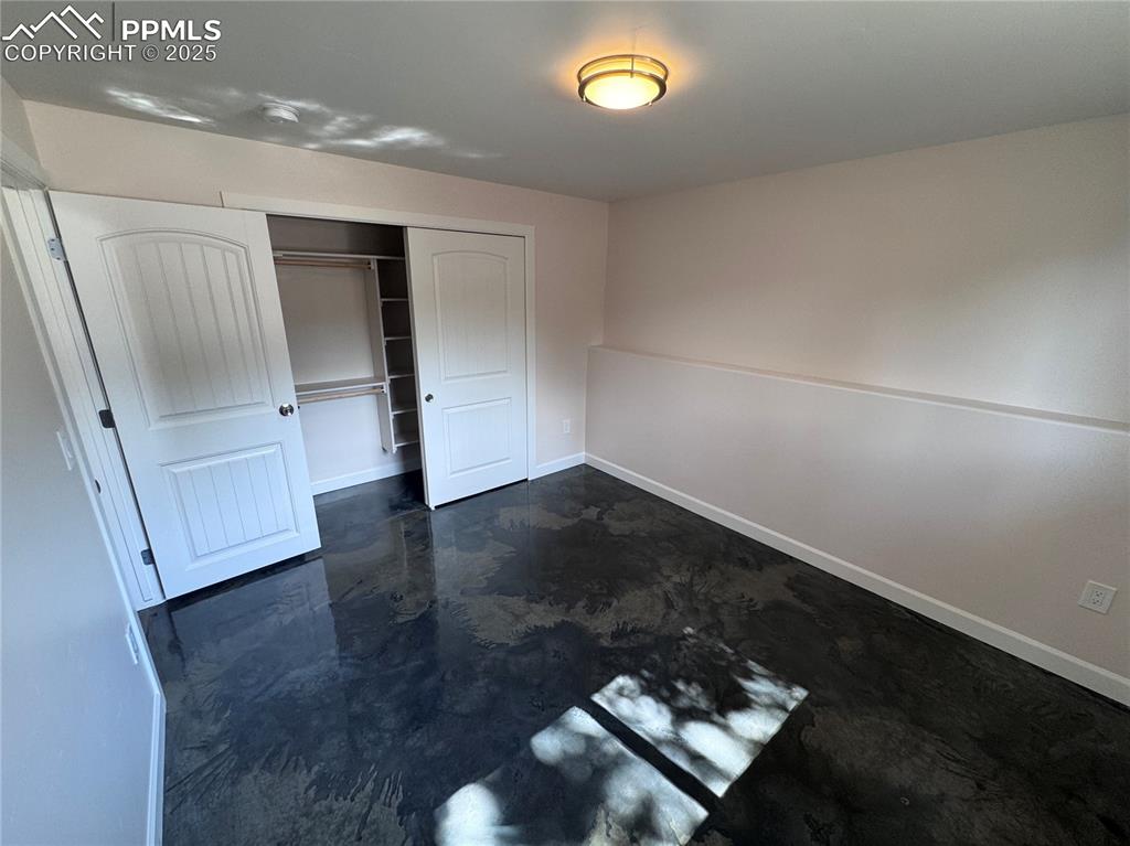 Unfurnished bedroom with a closet and finished concrete floors