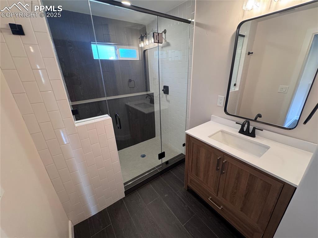 Bathroom with vanity, a shower stall, and dark wood finished floors