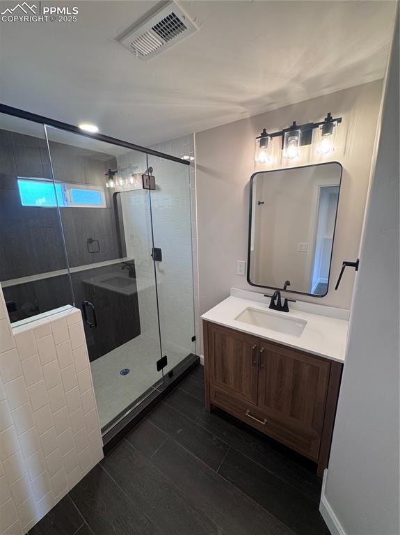 Bathroom with vanity, a shower stall, and dark wood-style flooring