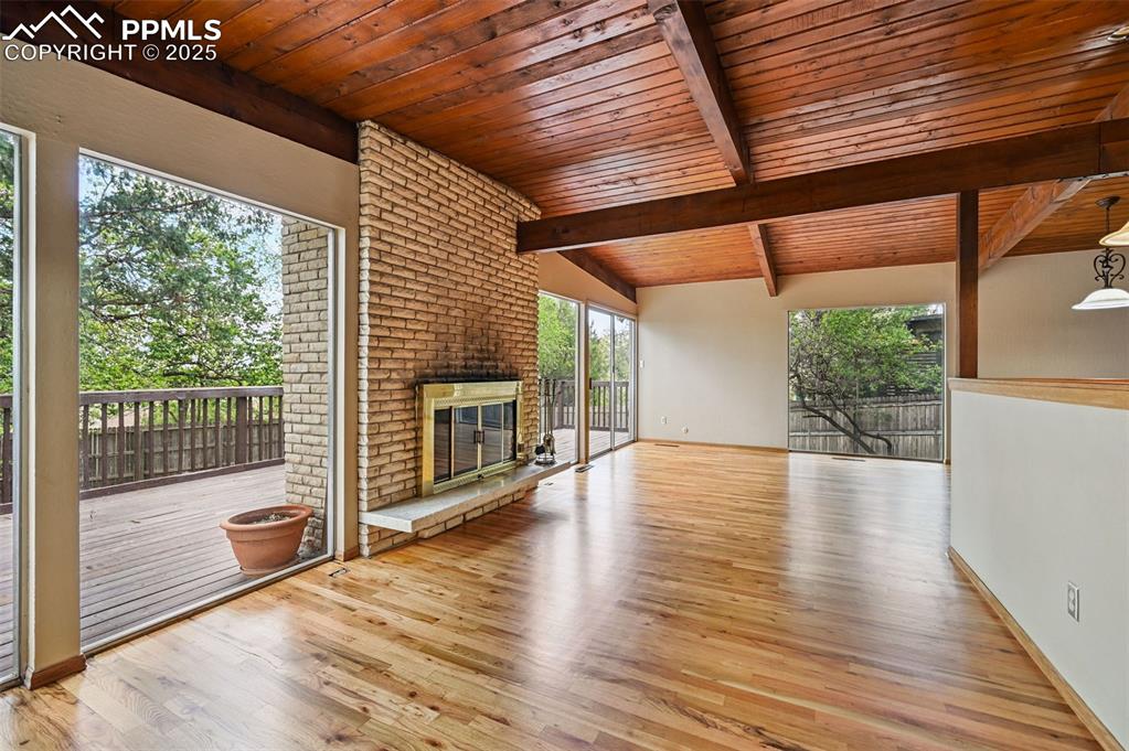  living room w/ wood ffloors, wooden ceiling, and brick fireplace