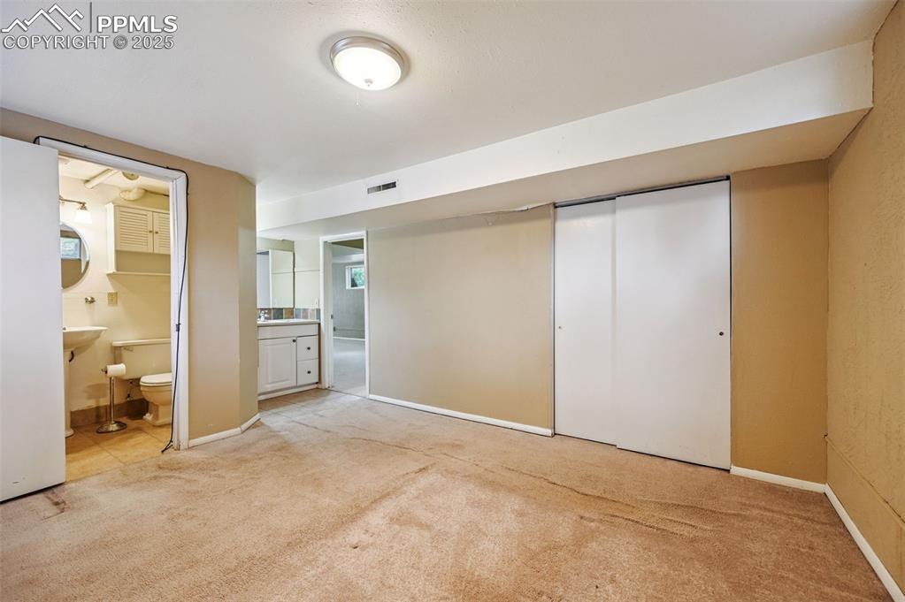 Unfurnished bedroom featuring light carpet, connected bathroom, and a closet