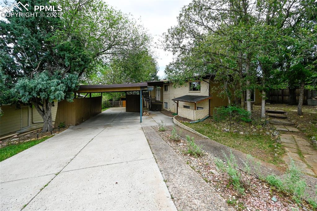 View of front facade with concrete driveway and a carport
