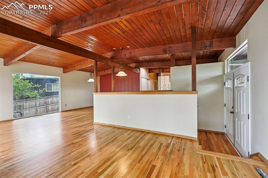 Unfurnished living room featuring a wooden ceiling with exposed beams and wood finished floors
