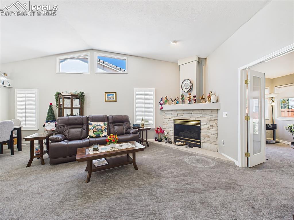 Living Room – Bright and airy living space with vaulted ceilings, clerestory windows, and a cozy gas fireplace with stone surround.